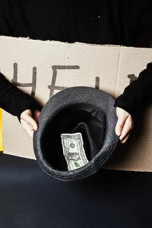Homeless person holding cardboard with HELP note and begging