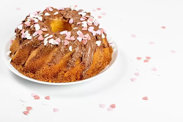 Homemade baking cupcake with milk chocolate and hearts decor on white background