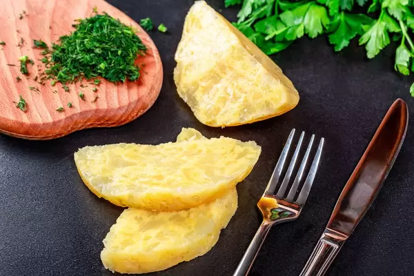Homemade cheese with fresh herbs, fork and knife
