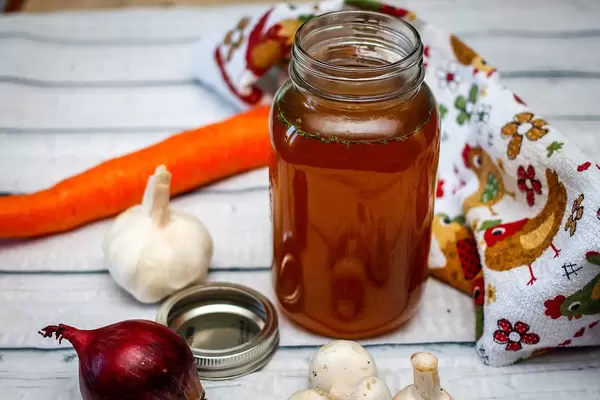 Homemade chicken stock in a jar, with onion and garlic