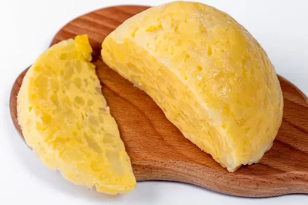 Homemade hard fat-free cheese on wooden board