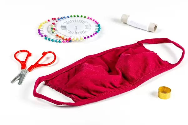 Homemade medical mask with thread and needles on a white background