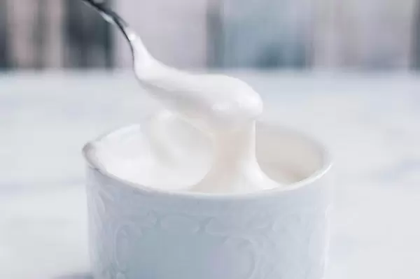 Homemade whipping cream on a spoon close up