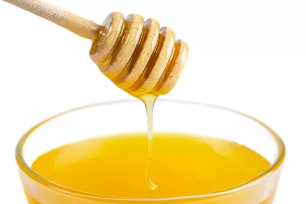 Honey bowl with dipper and flowing honey