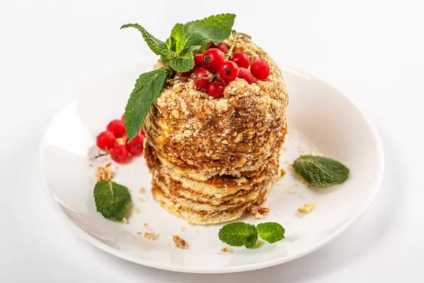 Honey cake with condensed milk, fresh mint leaves and red currant berries