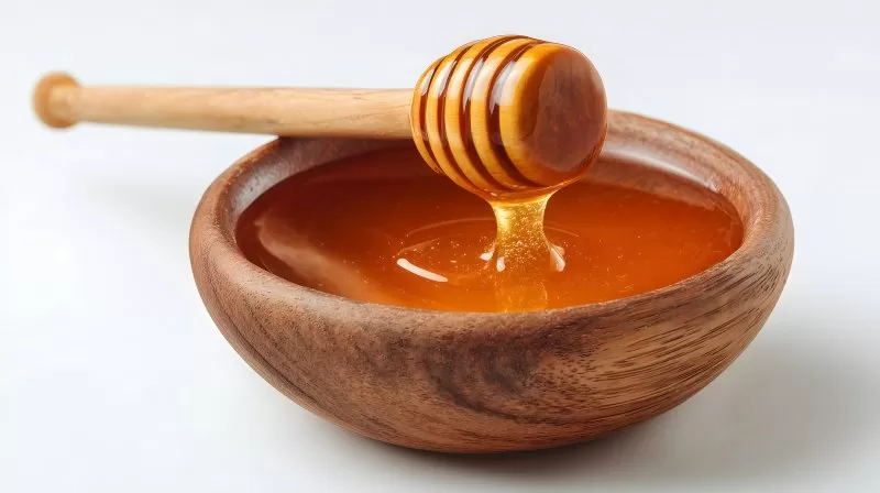 Honig in Holzschale mit Honiglöffel auf weißem Hintergrund