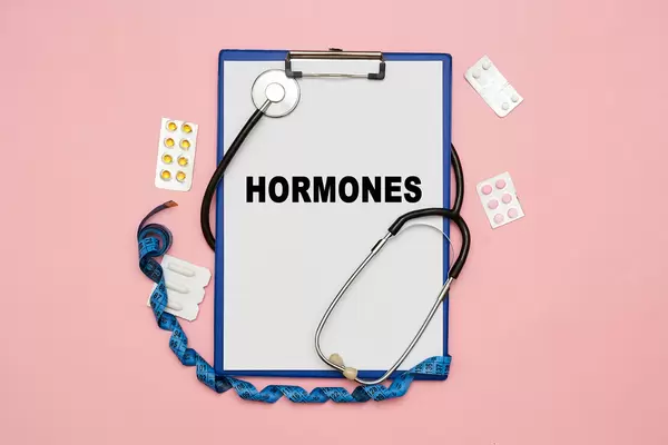 Hormones word on white paper card with medical equipments and pills
