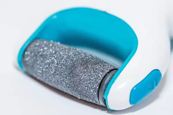 Hornhauthobel mit Rolle für gepflegte Füße durch Pediküre vor weißem Hintergrund