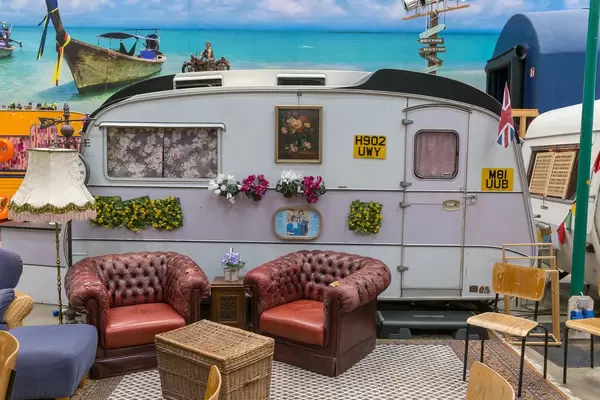 Hostel room at basecamp Boon is an old caravan decorated with pictures of Lady Di + Prince Charles, with living room & vintage red leather armchairs