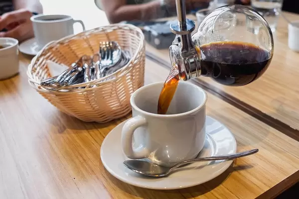 Hot coffee being poured in to mug, close up shot