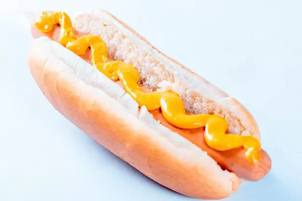 Hot dog with mustard on white