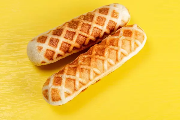 Hot dogs in waffles on a yellow background, top view