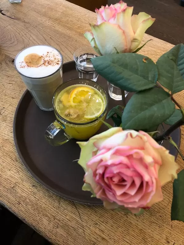 Hot orange drink with lemon and ginger, next to water and cream coffee