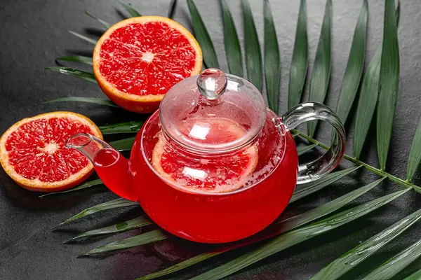 Hot tea with slices of fresh grapefruit on black background with green leaf (Flip 2019)