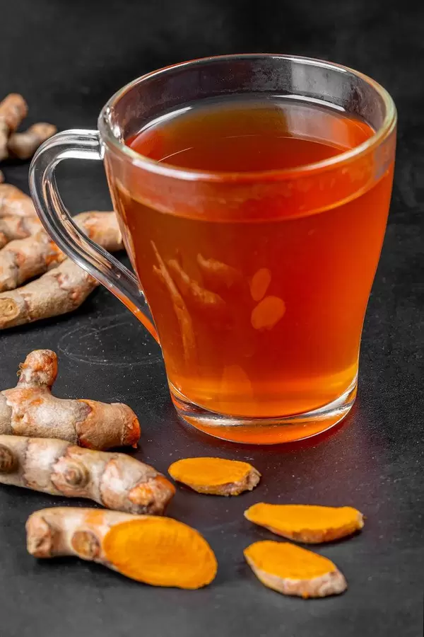 Hot turmeric drink with fresh turmeric roots on a black background (Flip 2020)