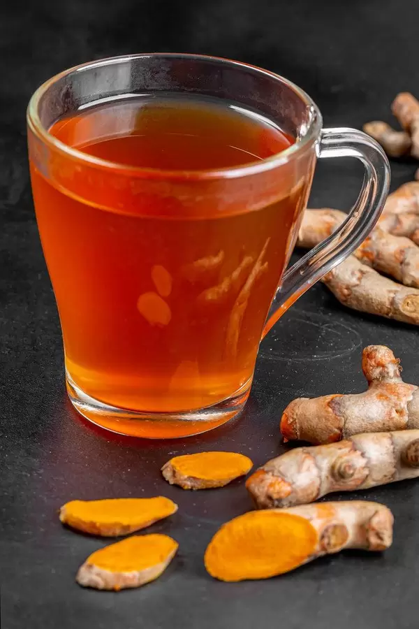 Hot turmeric drink with fresh turmeric roots on a black background