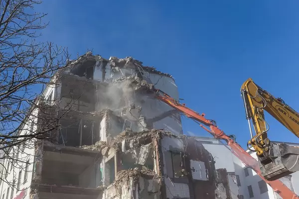 House Demolition with a Digger and a Crane at Blue Sky Weather