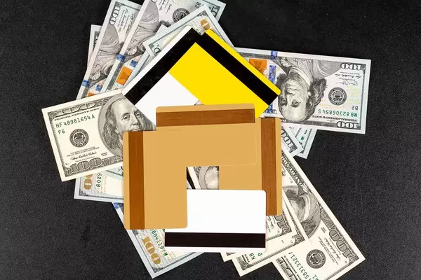 House made of credit cards on a pile of cash, top view