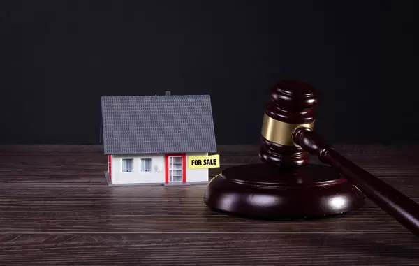 House with For sale text and wooden judge gavel