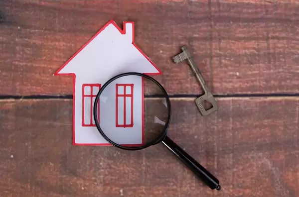 House with magnifying glass on wooden background