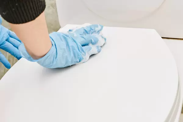 Housewife cleaning toilet seat cover with foamy sponge