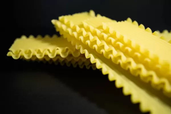 Hübsche Lasagneblätter mit gewelltem Rand vor schwarzem Hintergrund