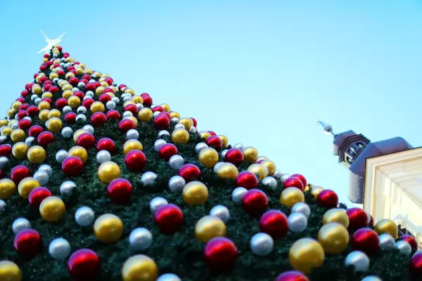 Huge Christmas tree with star on top, blue sky background