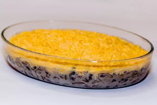 Hühnchen Julienne mit Pilzen in ovaler Glasschale vor weißem Hintergrund