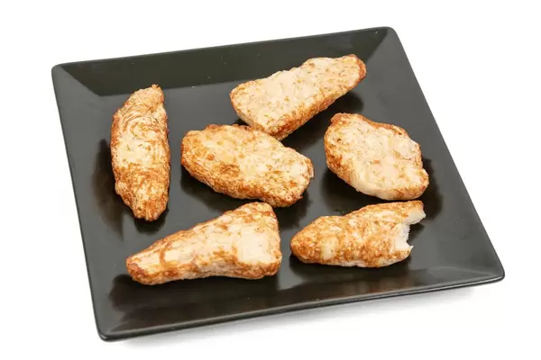 Hühnchenbrust in Chilisauce auf einem schwarzen, quadratischen Teller