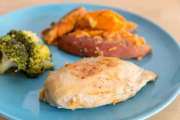 Hühnerbrust mit Broccoli und Süßkartoffeln auf einem Teller in der Nahaufnahme  - Bokeh