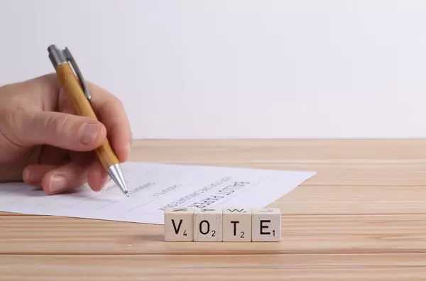 Human hand with ballot paper and vote text
