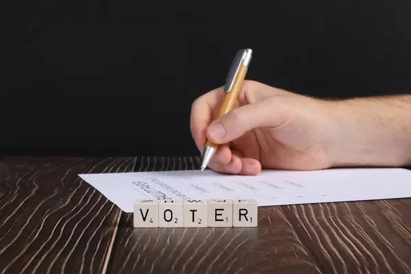 Human hand with ballot paper and voter text