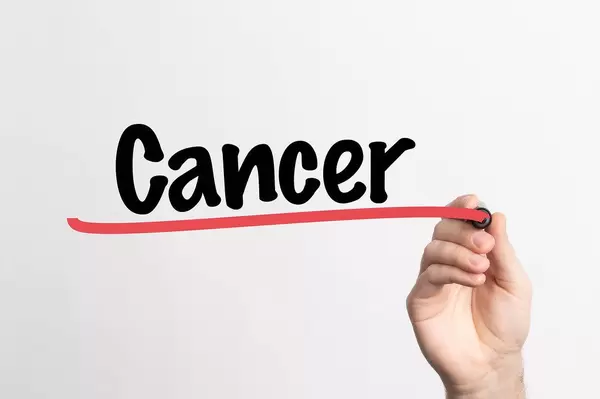 Human hand writing Cancer on whiteboard
