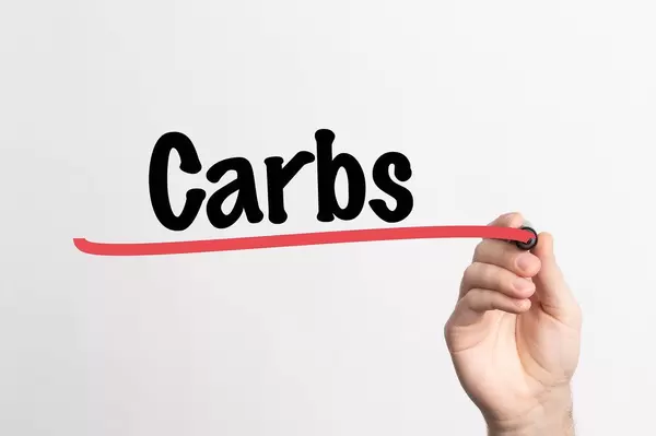Human hand writing Carbs on whiteboard
