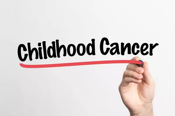 Human hand writing Childhood Cancer on whiteboard
