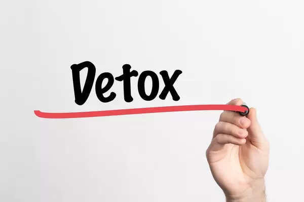 Human hand writing Detox on whiteboard