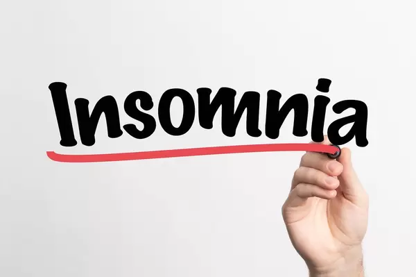 Human hand writing Insomnia on whiteboard