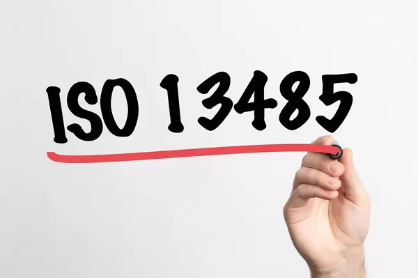 Human hand writing ISO 13485 on whiteboard