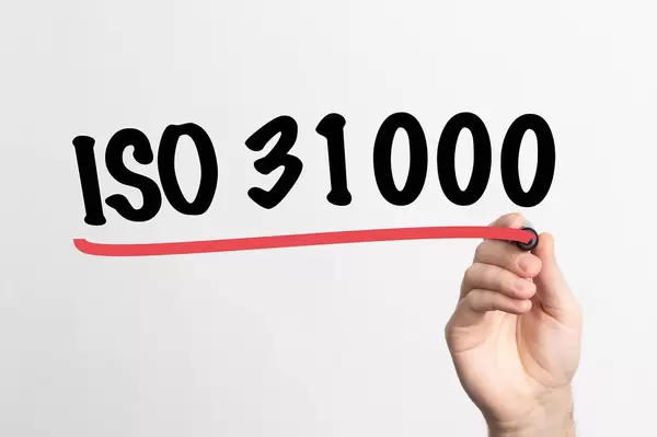 Human hand writing ISO 31000 on whiteboard