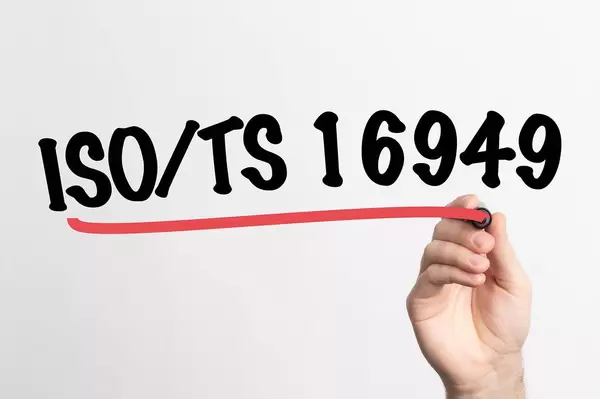Human hand writing ISO/TS 16949 on whiteboard