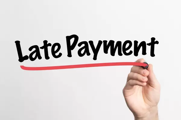 Human hand writing Late Payment on whiteboard