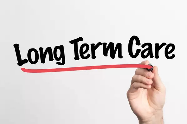 Human hand writing Long Term Care on whiteboard