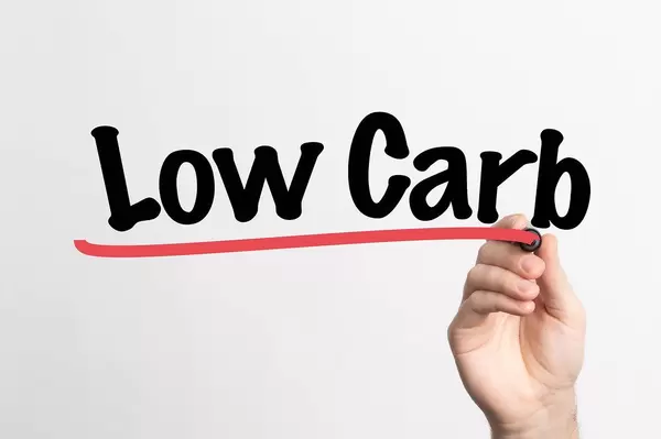 Human hand writing Low Carb on whiteboard