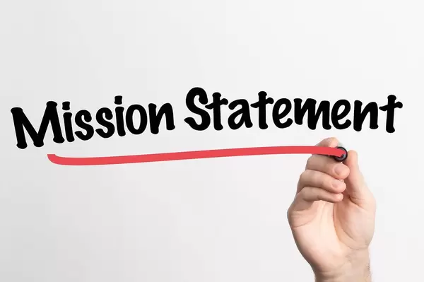 Human hand writing Mission Statement on whiteboard