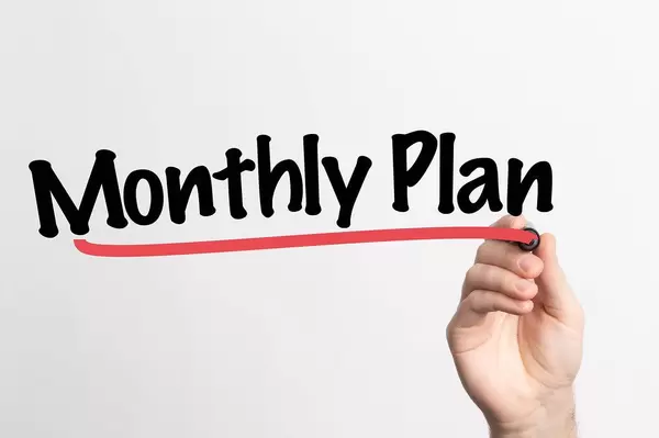 Human hand writing Monthly Plan on whiteboard