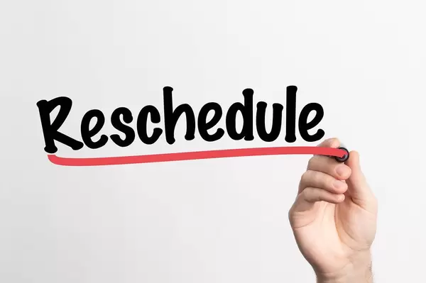 Human hand writing Reschedule on whiteboard