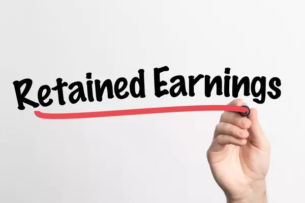 Human hand writing Retained Earnings on whiteboard
