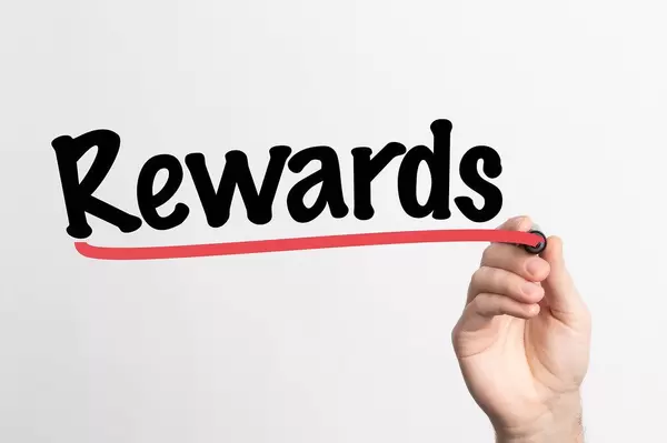 Human hand writing Rewards on whiteboard