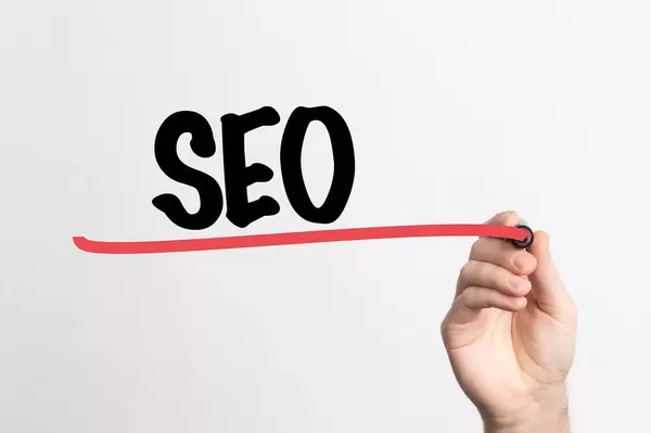 Human hand writing SEO on whiteboard