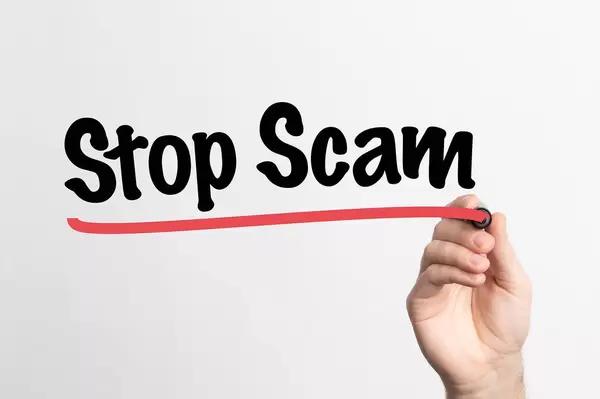 Human hand writing Stop Scam on whiteboard